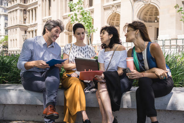 Beautiful mature business people networking outdoors after work in a public park.